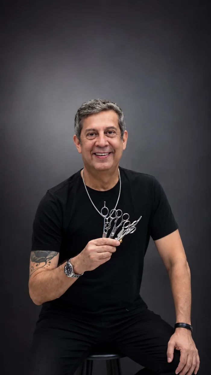 Edu Domingos sentado, segurando um leque de tesouras